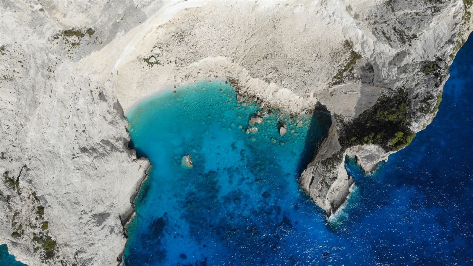 Aerial view of white limestone cliffs meeting deep blue Aegean water